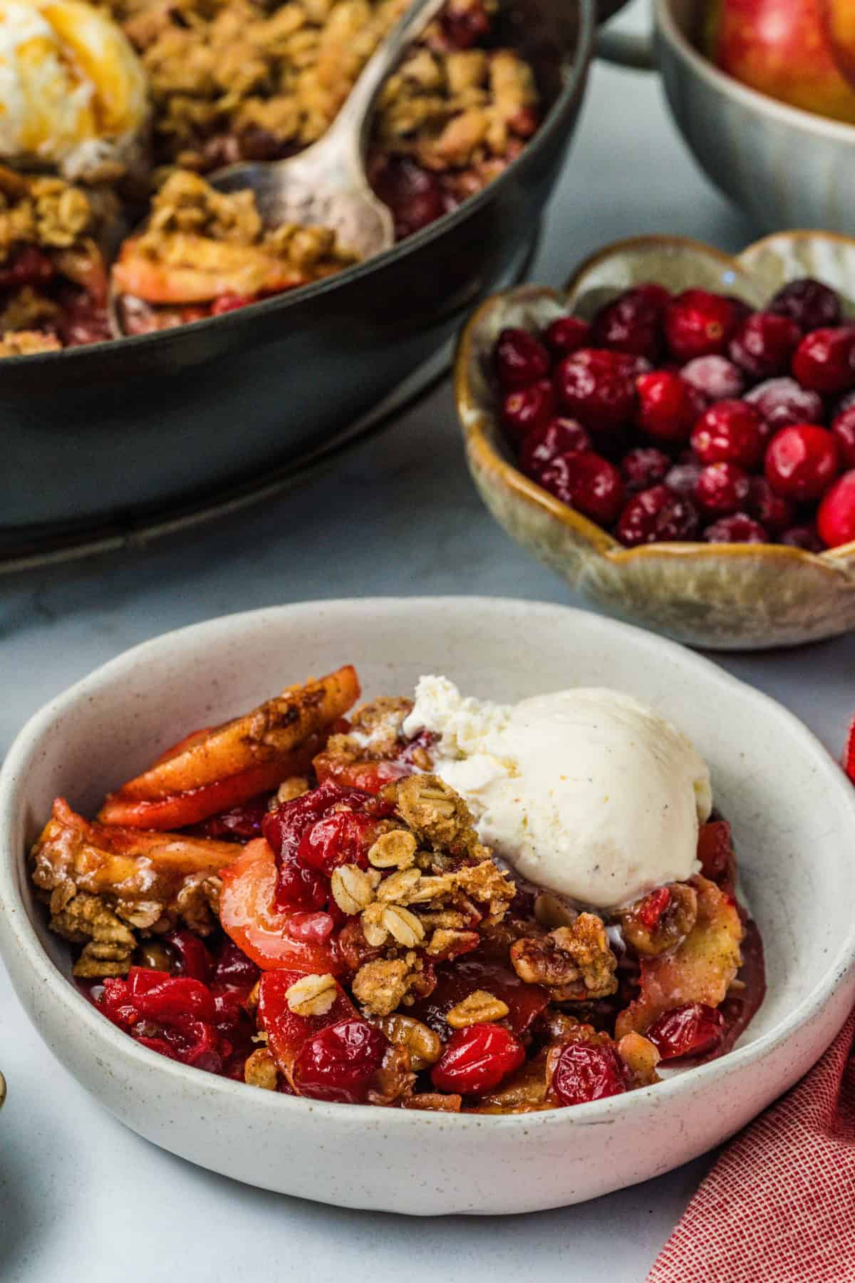 This Apple Cranberry Crisp is baked in a cast-iron skillet, giving the fruit a caramelized edge while the buttery oat turns golden & crunchy. Cranberry Apple Crisp in a bowl with ice cream