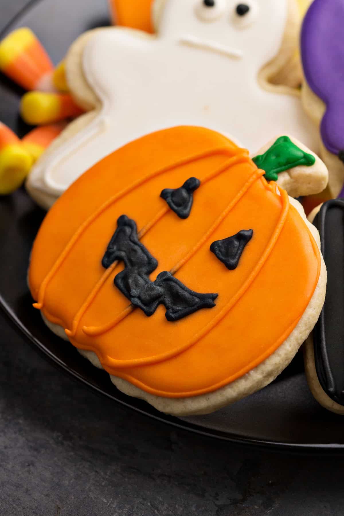 These Halloween Sugar Cookies are soft, buttery cut-out cookies decorated with colorful icing for a fun and festive Halloween treat. Close up of a pumpkin sugar cookie decorated with icing.